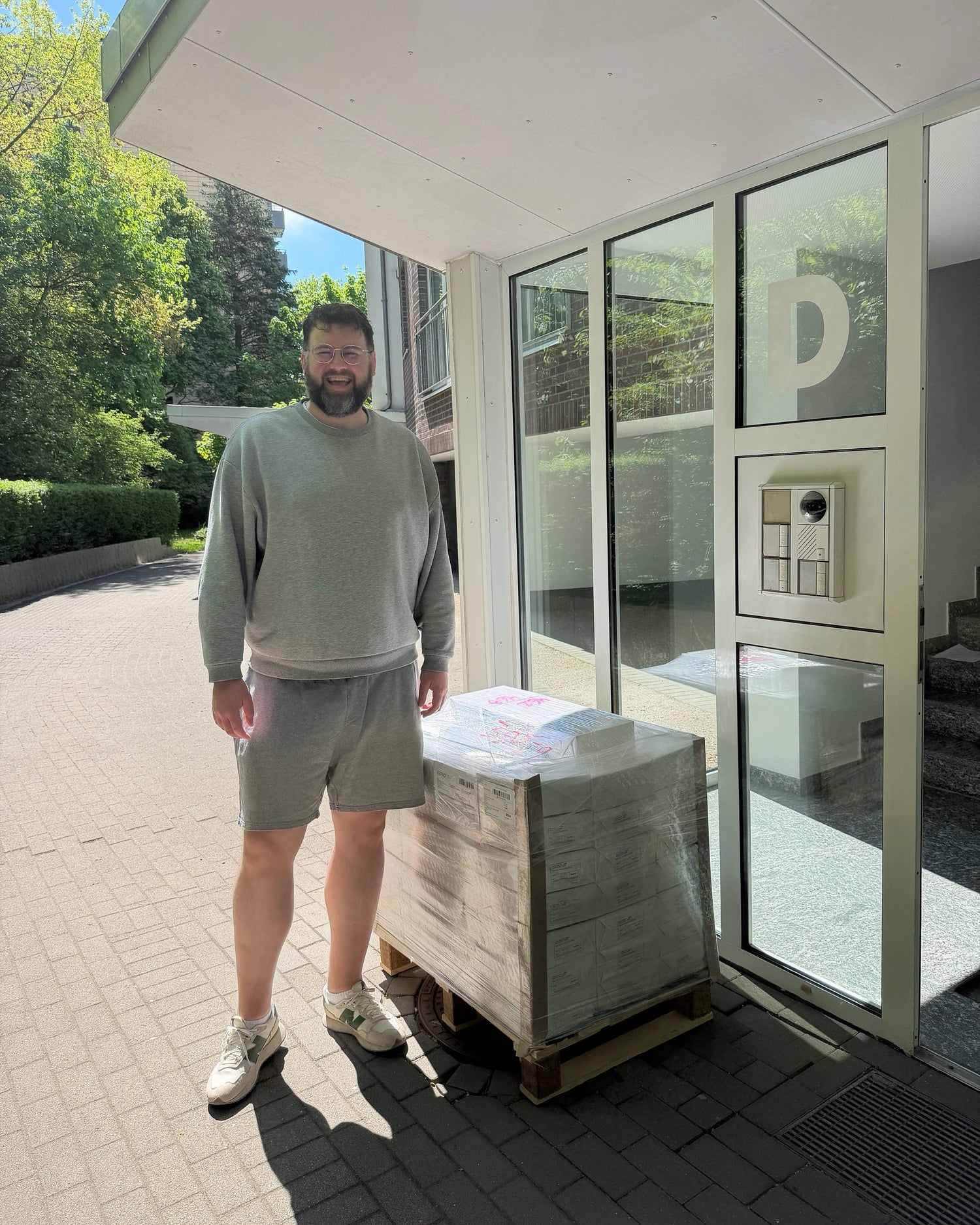 Man standing next to a pallet with BOTANICA coloring books outside a building